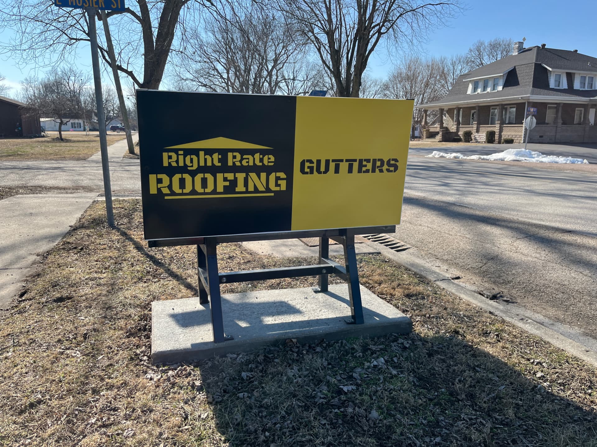 Right Rate Roofing and Gutters Benchboard installed at a street corner
